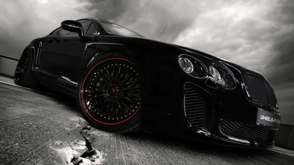 Black sports car on open road under dramatic clouds symbolizing power and adventure wallpaper