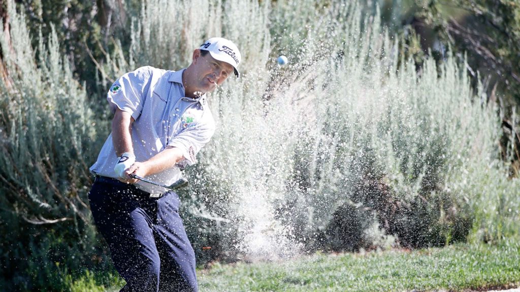 Professional golfer hitting powerful bunker shot with sand spray vivid green golf course background Wallpaper