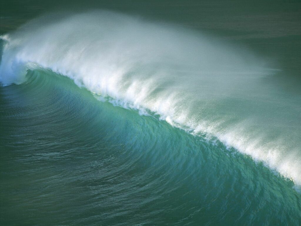 Powerful curling ocean wave with foamy spray in deep blue and turquoise California waters wallpaper