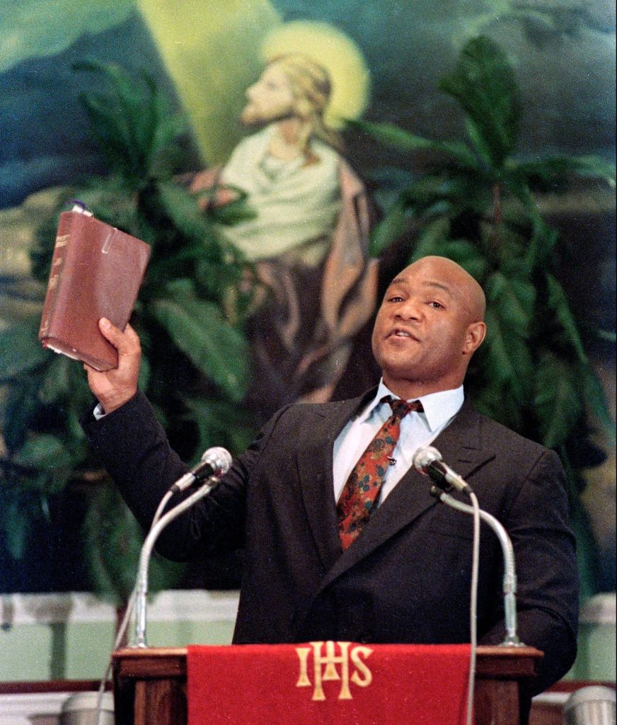 George Foreman preaching at pulpit holding Bible inspiring boxing legend faith mural background wallpaper