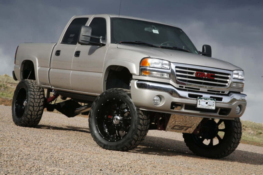 Gray lifted GMC truck in desert landscape under dramatic sky rugged terrain wallpaper background