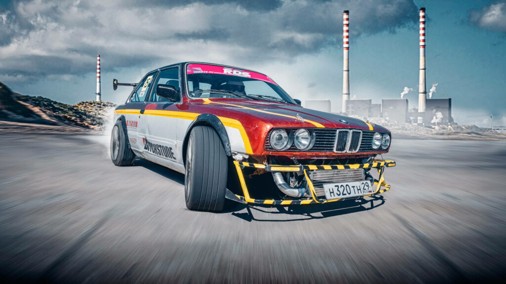 Modified race car drifting on open road with smoke aggressive stance industrial background Wallpaper