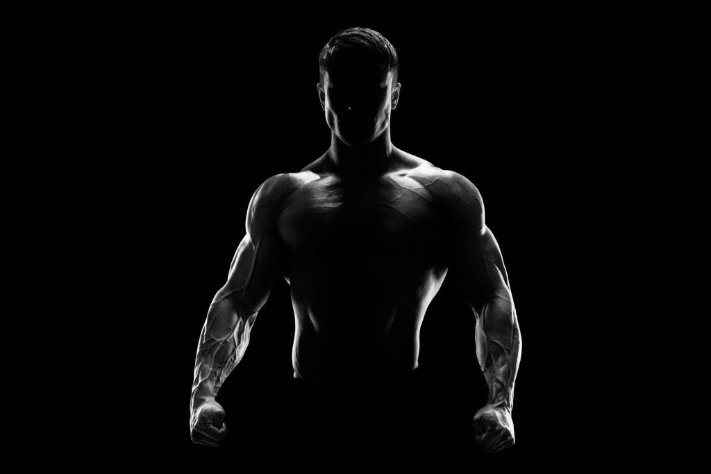 Silhouette of muscular man with dramatic rim lighting fitness wallpaper strength motivation