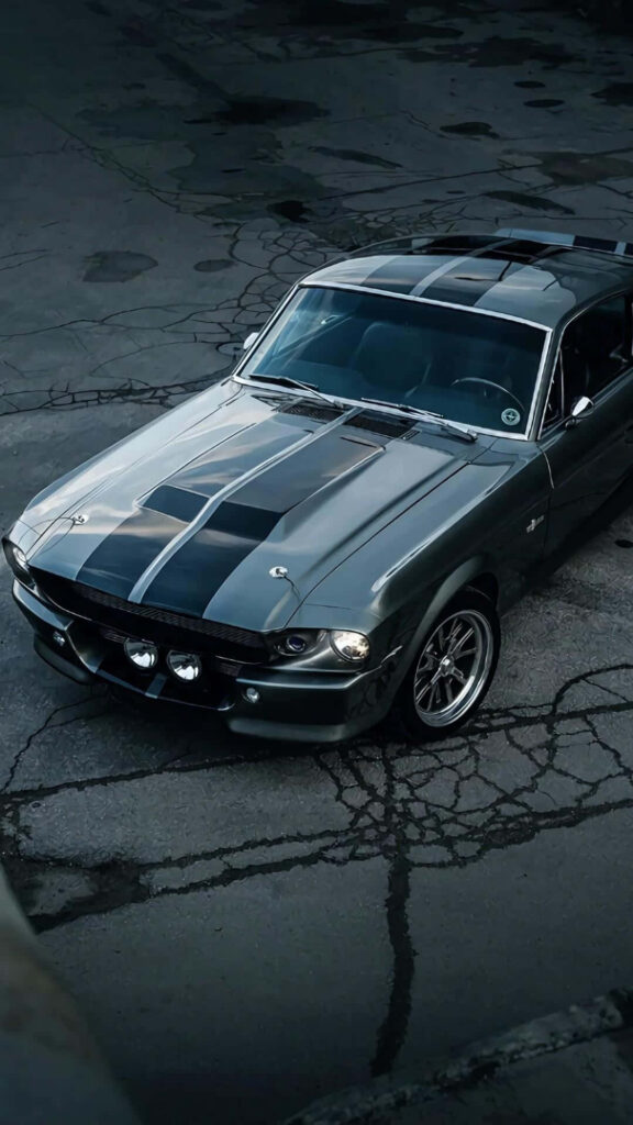 Sleek Mustang sports car with racing stripes on cracked pavement dynamic iPhone wallpaper background
