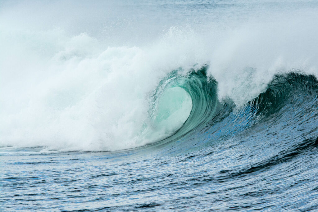 Powerful curling ocean wave wallpaper with vivid blue water and detailed white foam textures
