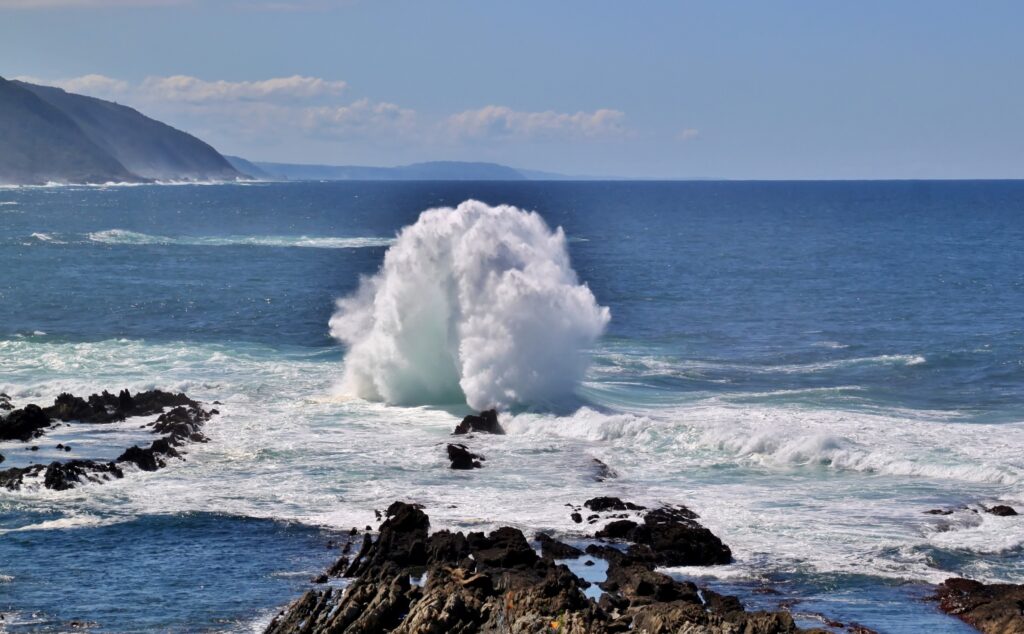 Powerful sea waves crashing rugged rocks white surf deep blue ocean clear sky dynamic wallpaper