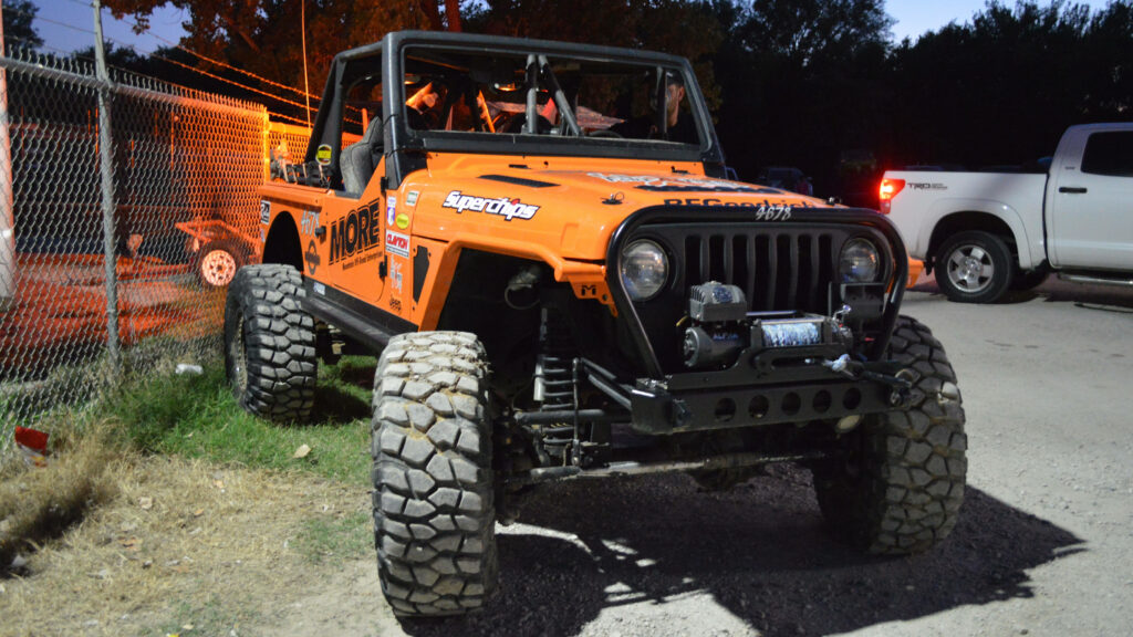 Orange Thar off-road vehicle on rugged terrain with robust tires, adventure 4K wallpaper background