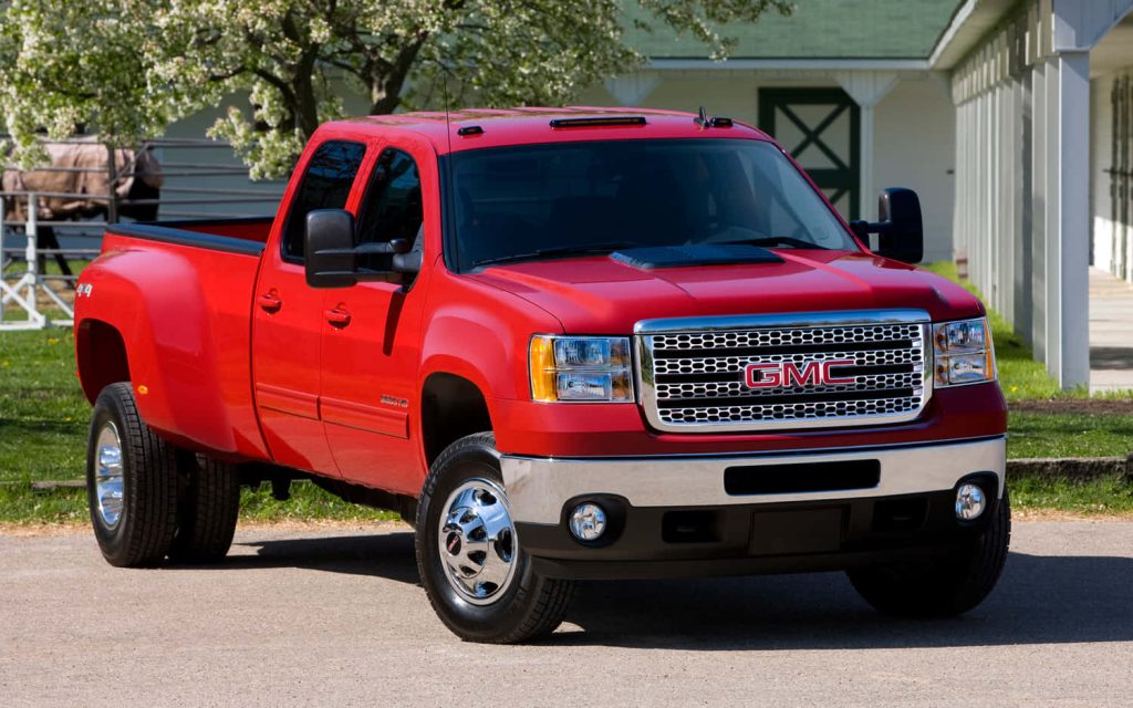 Bright red GMC Sierra 3500HD dually with chrome grille in sunny rural landscape wallpaper