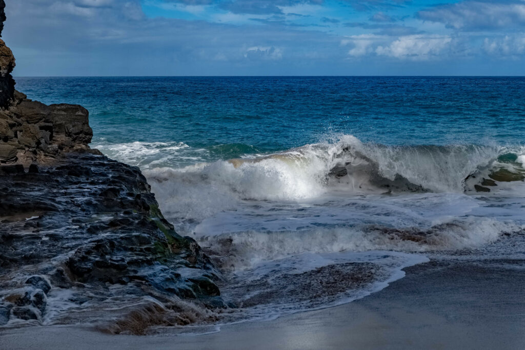 Powerful surf crashing on rugged coastal rocks with foamy waves and serene blue sea wallpaper