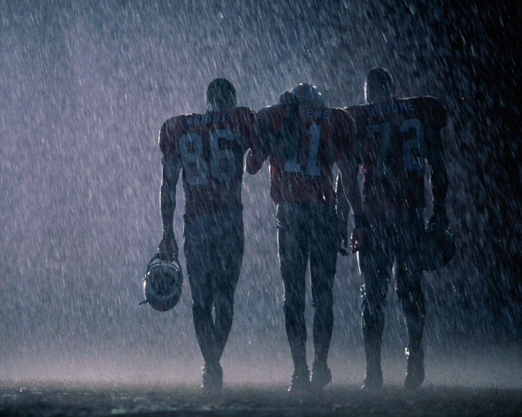 Gridiron Warriors: United in the Rain - An Enthralling NFL Football Background Wallpaper