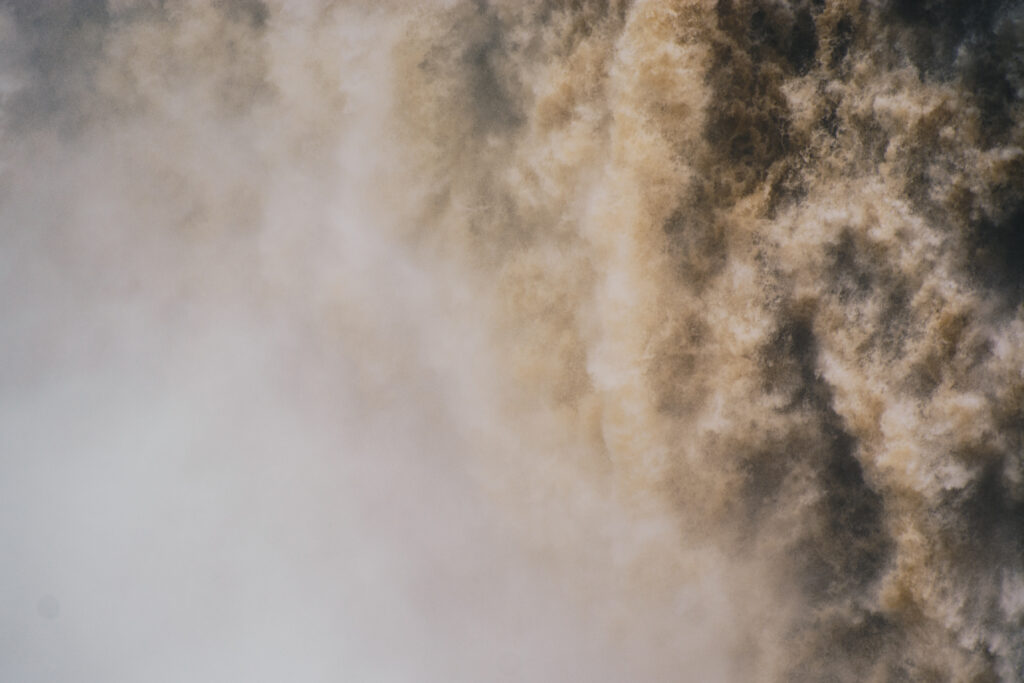 Dramatic waterfall wallpaper with cascading water mist and natural brown white tones in motion