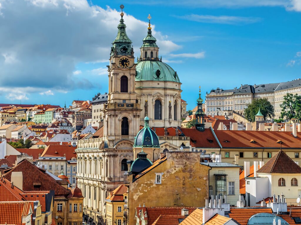 Prague Clock Tower over terracotta rooftops historic Baroque architecture bright blue sky wallpaper