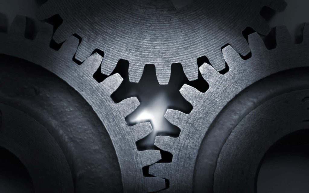 Close-up of interlocking metal gears with glowing center industrial mechanical wallpaper background
