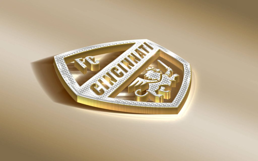 Premium 3D FC Cincinnati crest wallpaper with gold silver metallic winged lion on warm background