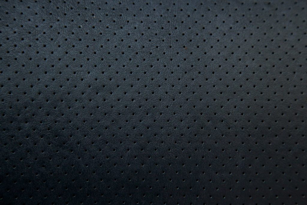 Close-up of perforated black leather wallpaper with matte finish and modern minimalist texture