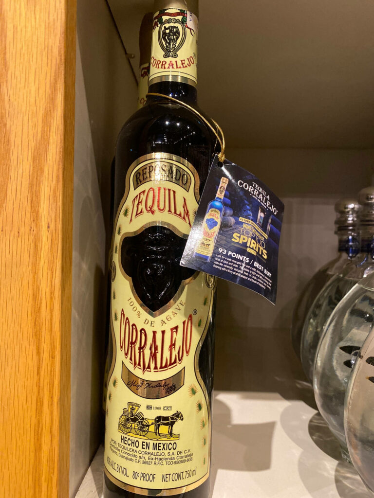 Corralejo Tequila Reposado bottle on shelf with warm lighting highlighting golden label and design Wallpaper