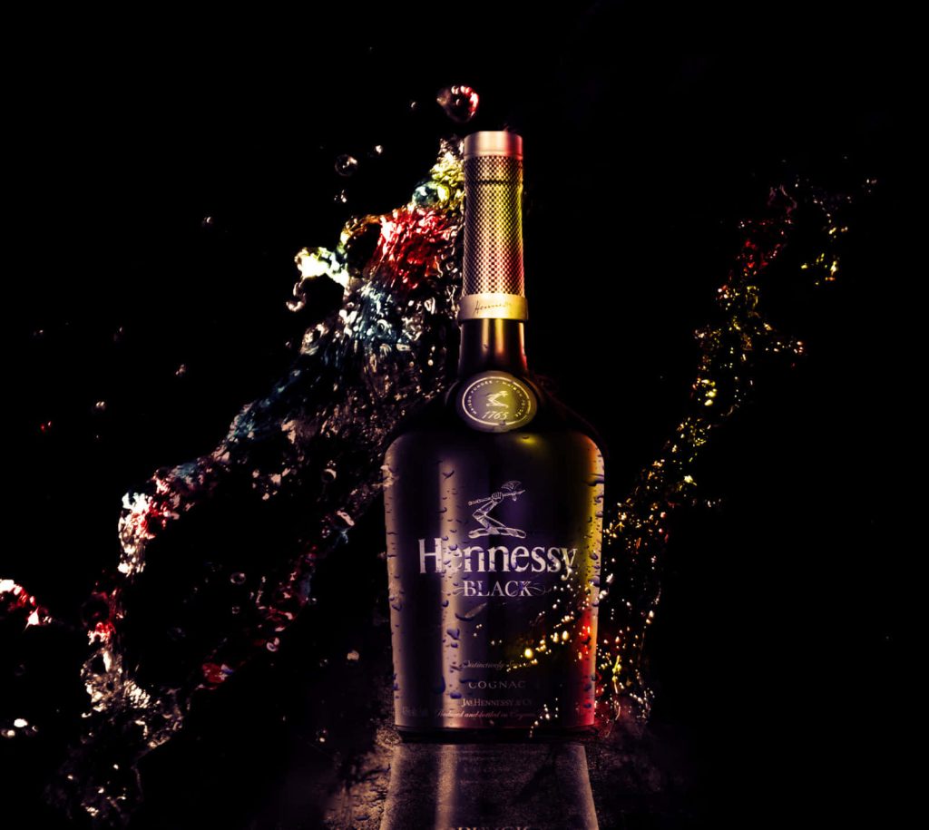 Hennessy Black cognac bottle with dynamic liquid splash on sleek black background wallpaper