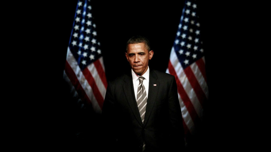 President Barack Obama stands solemnly before two American flags preparing to address rally wallpaper background