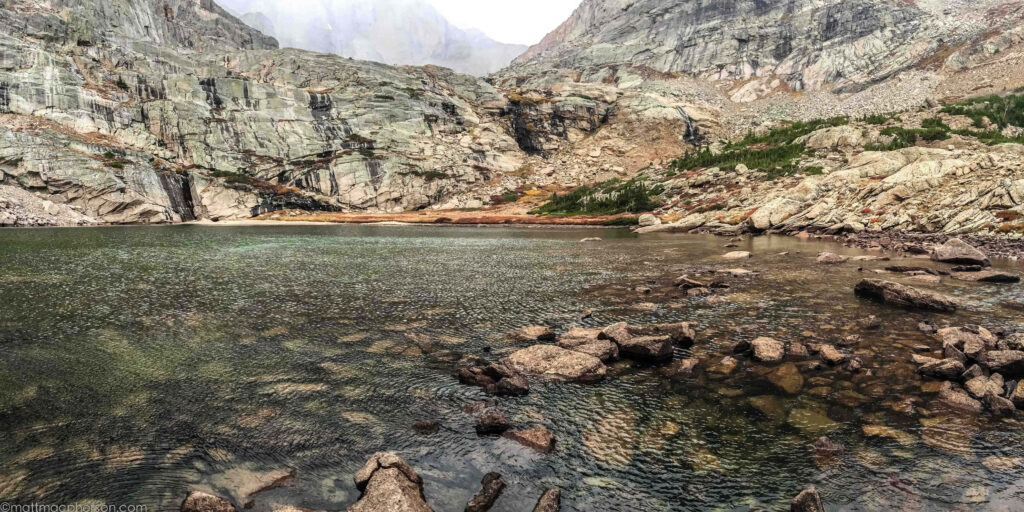 Primordial desolate Colorado lake with rugged cliffs and sparse vegetation natural landscape wallpaper