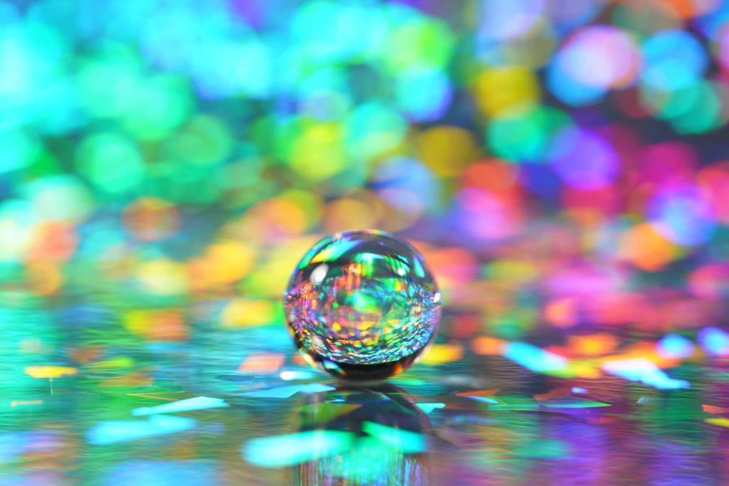 Macro photo of water drop on prismatic surface with vibrant rainbow holographic bokeh light Wallpaper