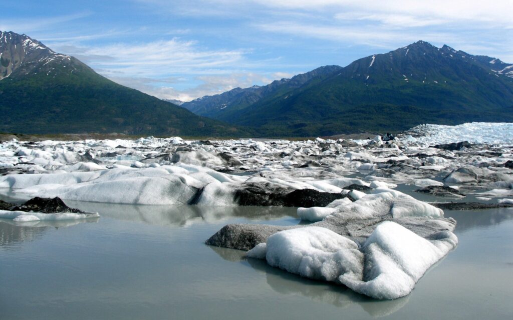 Coastal arctic landscape with snowy shore icy water rugged mountains and green slopes wallpaper
