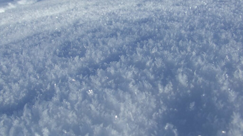 Close-up macro of delicate snowflakes and ice crystals showcasing pristine winter texture Wallpaper