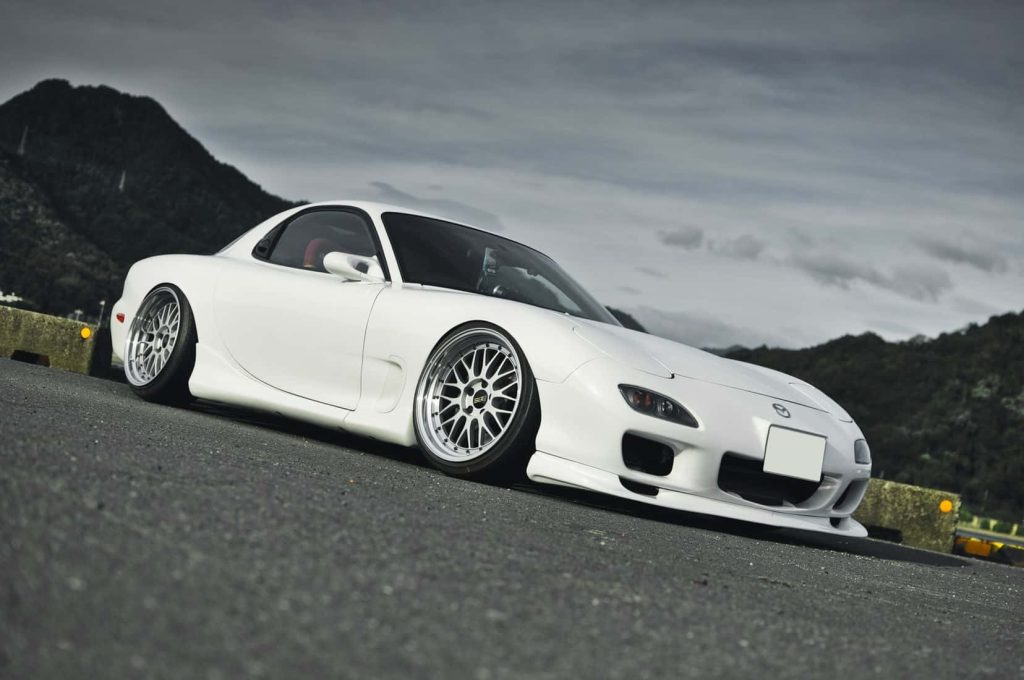White Mazda RX-7 FD3S slammed JDM sports car with silver mesh wheels on moody mountain road Wallpaper