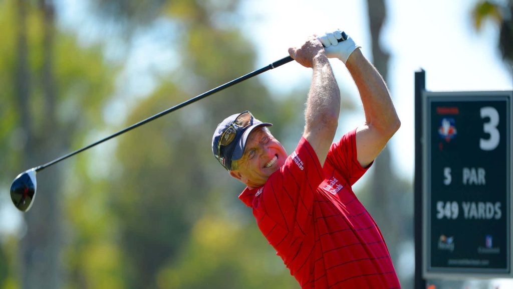 Professional Golfer Fred Funk mid-swing driving on sunlit golf course at Par 5 549-yard hole Wallpaper