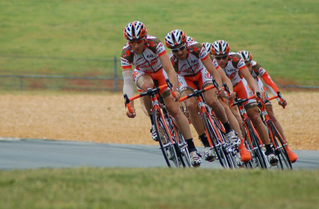 Professional cycling team in matching gear racing on winding outdoor track showing teamwork speed Wallpaper