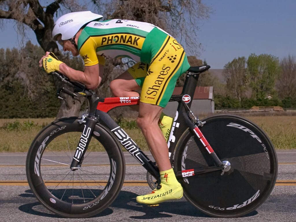 Professional cyclist in yellow green Phonak kit rides aero time trial bike with carbon wheels Wallpaper