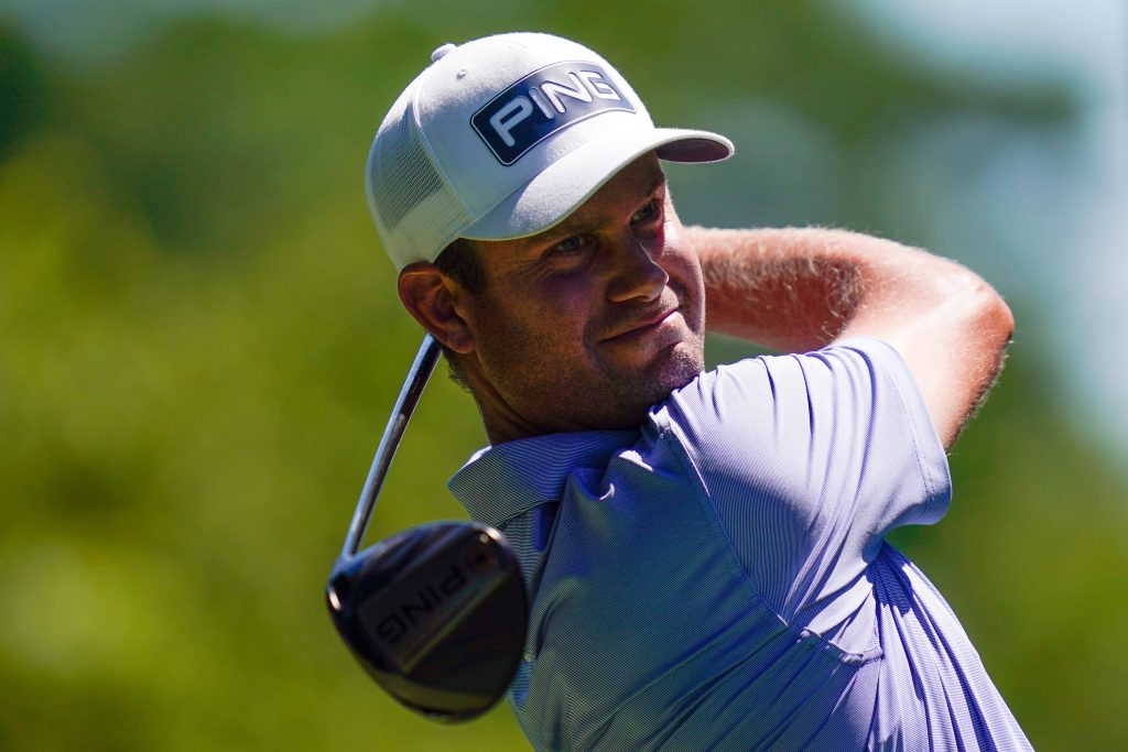 Professional golfer swinging PING driver close-up with white cap and blue shirt in green background Wallpaper