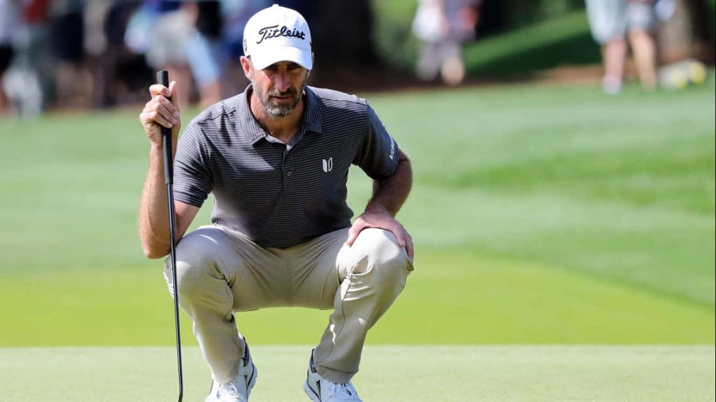Professional golfer reading green line focused in striped shirt Titleist cap on lush golf course Wallpaper