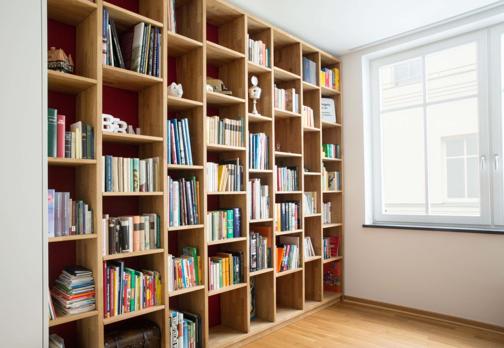 Professional home library video call background with wooden bookshelf books trophy and warm red wall Wallpaper