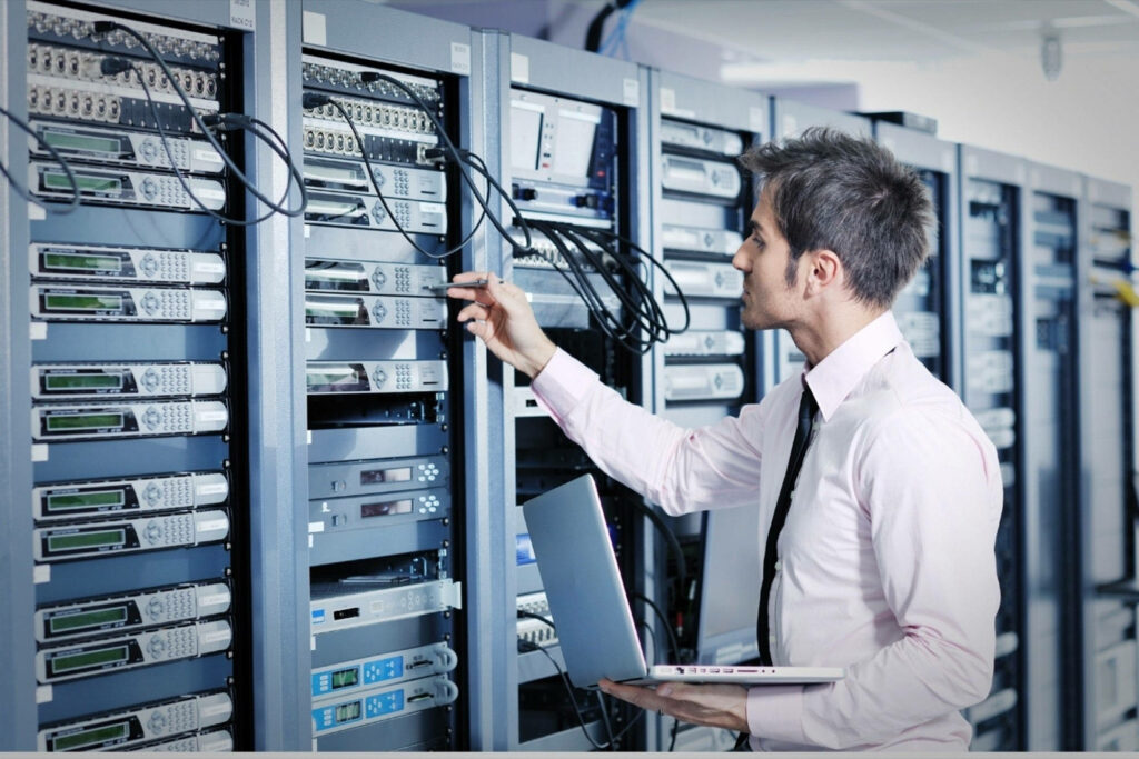 Professional Technician Inspects Server Racks with Laptop - Wallpaper