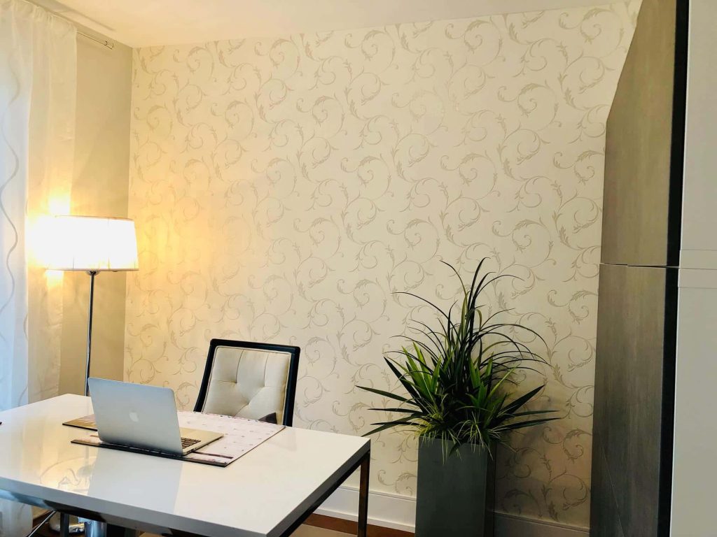 Professional virtual office with white desk cushioned chair floor lamp cream floral wallpaper plant
