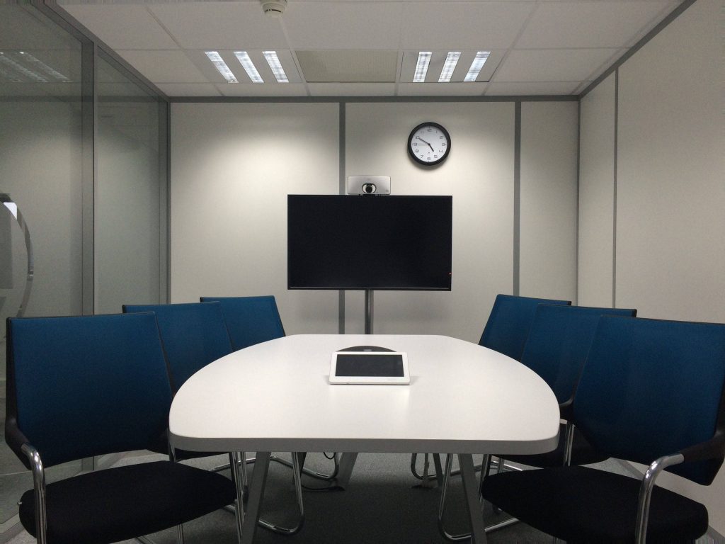 Professional Zoom background small office conference room white table tablet blue chairs wall display Wallpaper