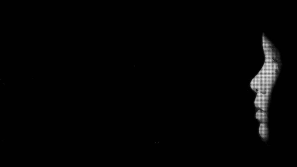 Minimalist grayscale side profile wallpaper with digital halftone pattern on pure black background