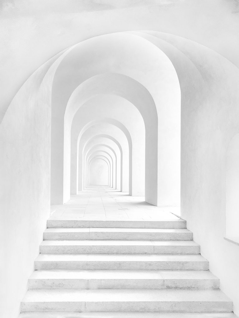 Pure White Archway wallpaper with minimalist corridor and receding arches for modern elegance