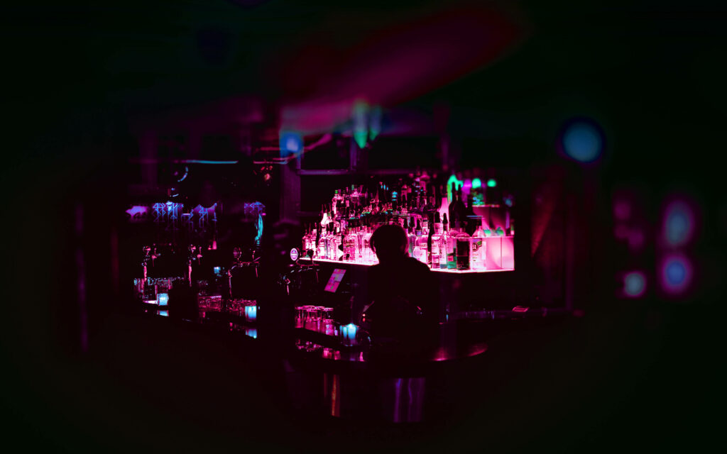 Nightlife Vibes: Stunning Neon Bar Decor Illuminating a Silhouette of a Man Wallpaper