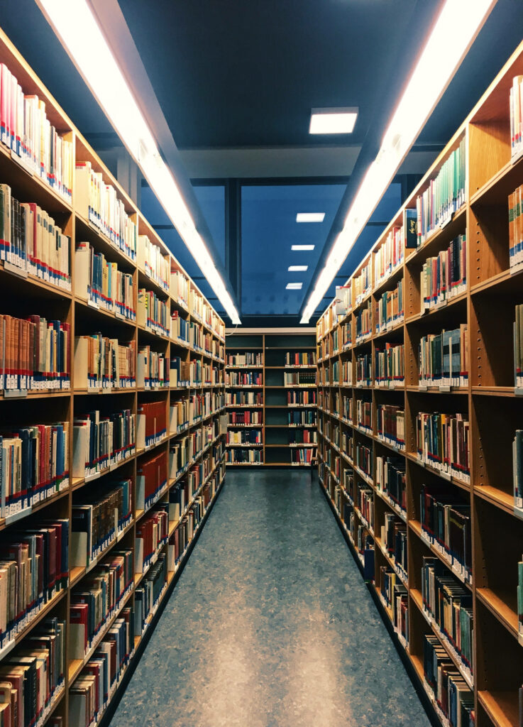 Quiet library aisle with colorful books tall shelves modern ceiling and natural window light Wallpaper