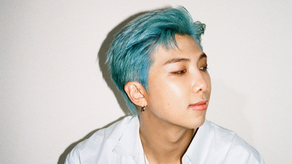 Portrait of BTS leader RM with vibrant blue hair on a minimalist serene background wallpaper