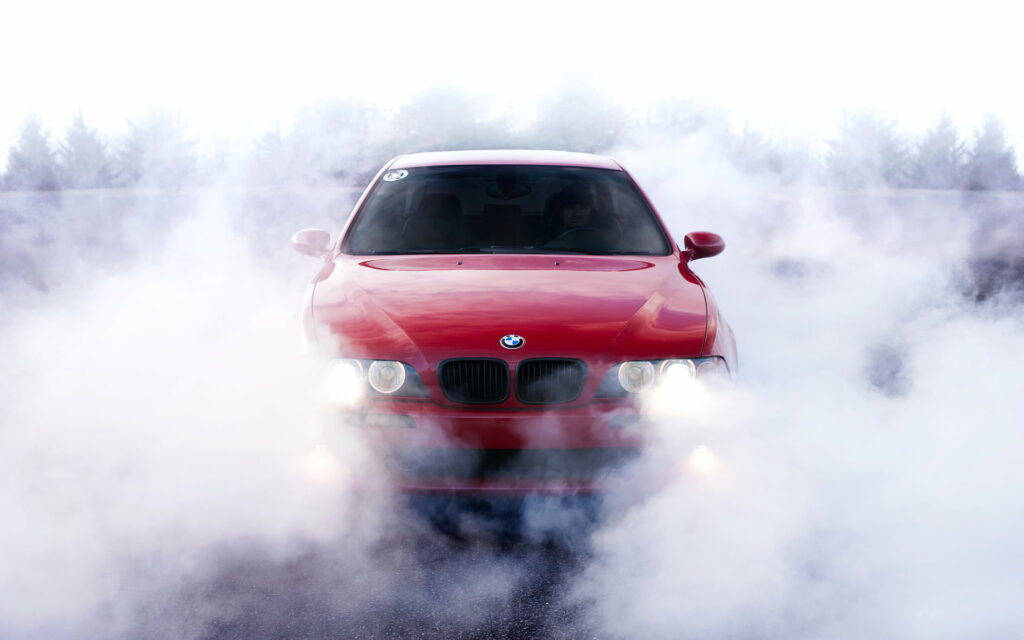 Red BMW E39 5 Series burnout with thick tire smoke and bright headlights automotive wallpaper