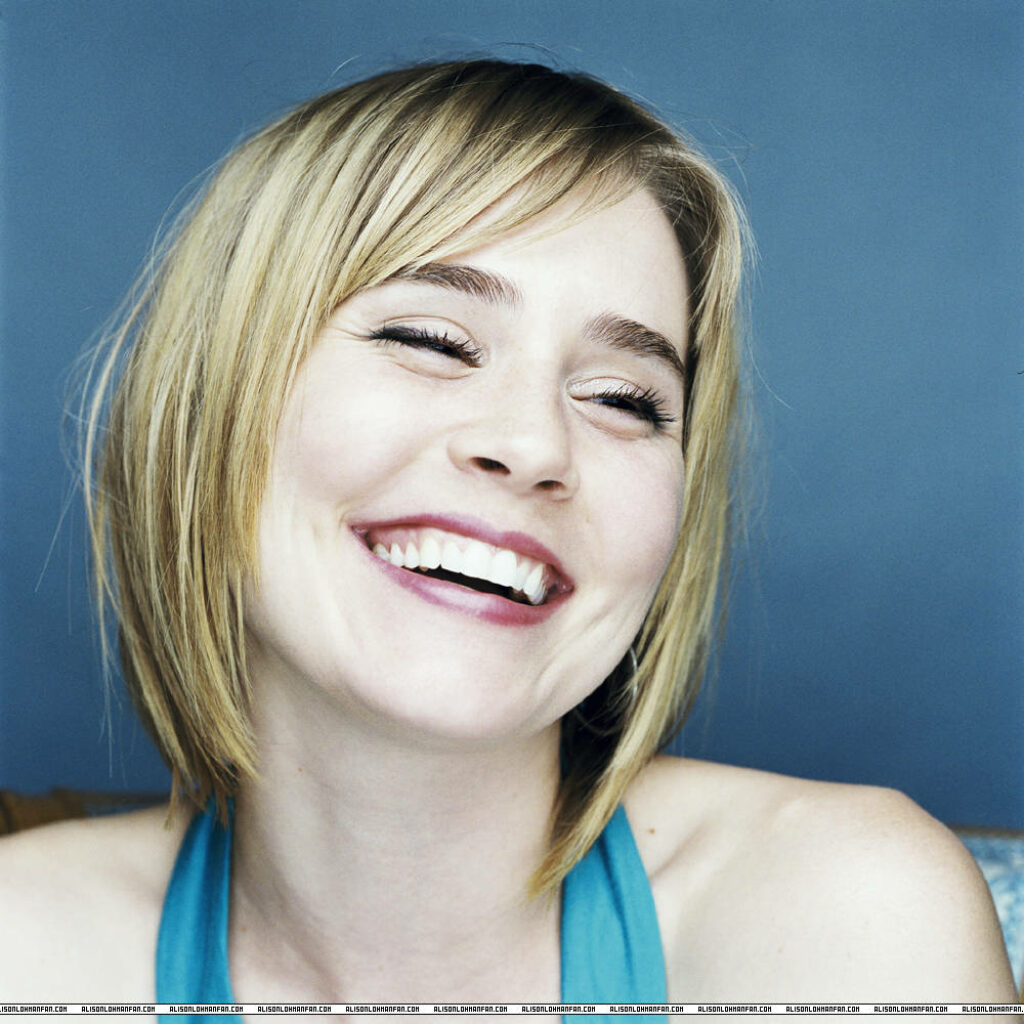 Alison Lohman smiling brightly against soft blue background cheerful vibrant wallpaper