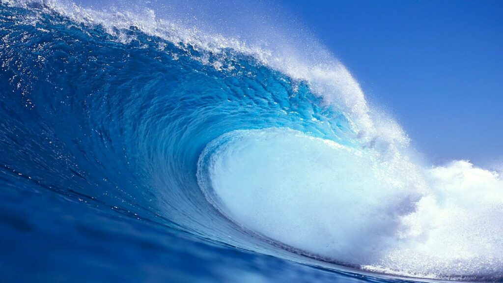 Powerful ocean wave crest with blue white hues sunlight highlights dynamic surfing energy wallpaper