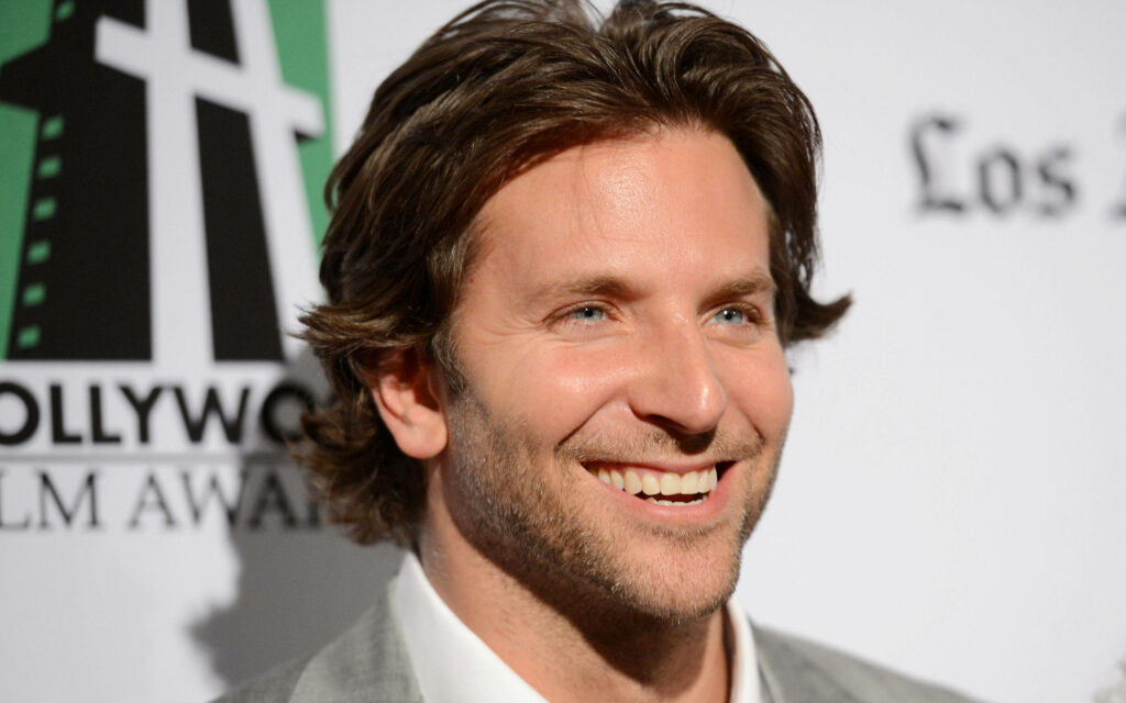 Bradley Cooper smiling in light suit relaxed pose bright wallpaper background portrait
