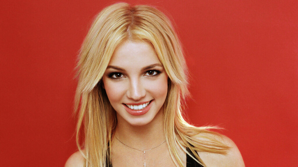 Radiant Britney Spears Wallpaper: Innocence & Charm on Red Background