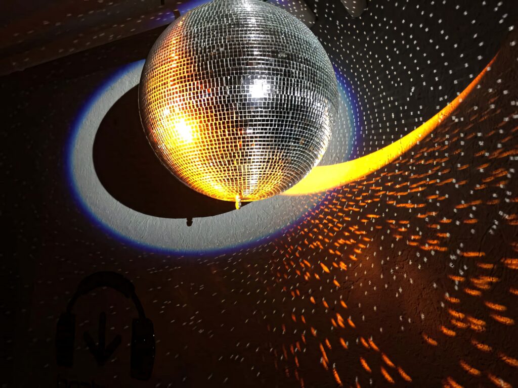 Radiant disco ball casting vibrant reflections on dark room vibrant night party wallpaper background