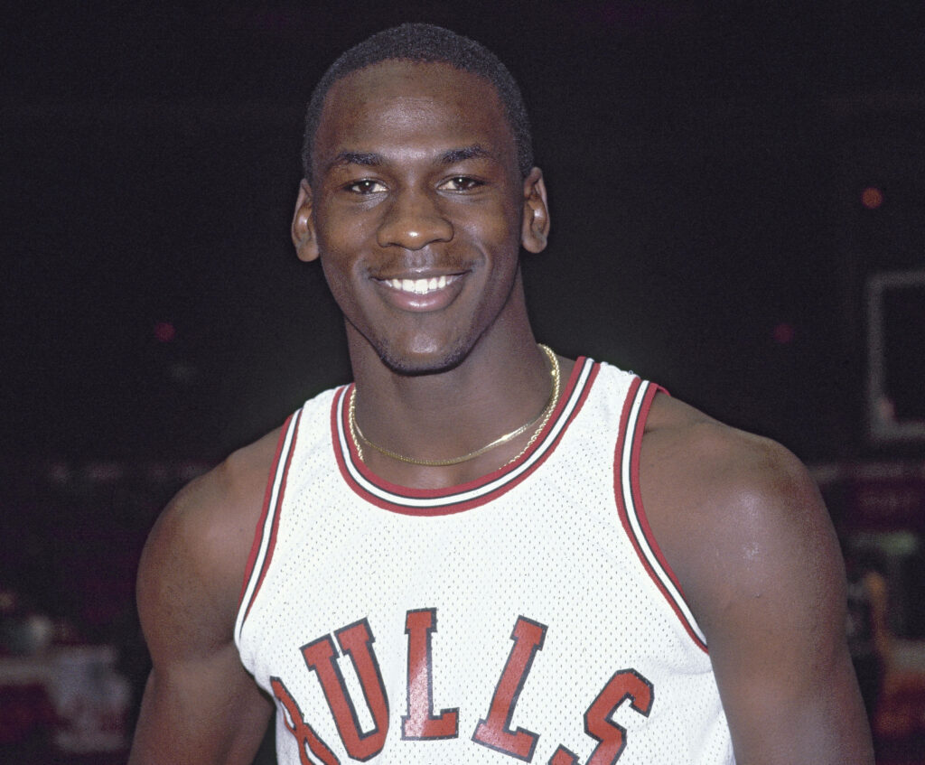 The Grinning Legend: Michael Jordan Exuding Charisma in Iconic Bulls Gear Wallpaper