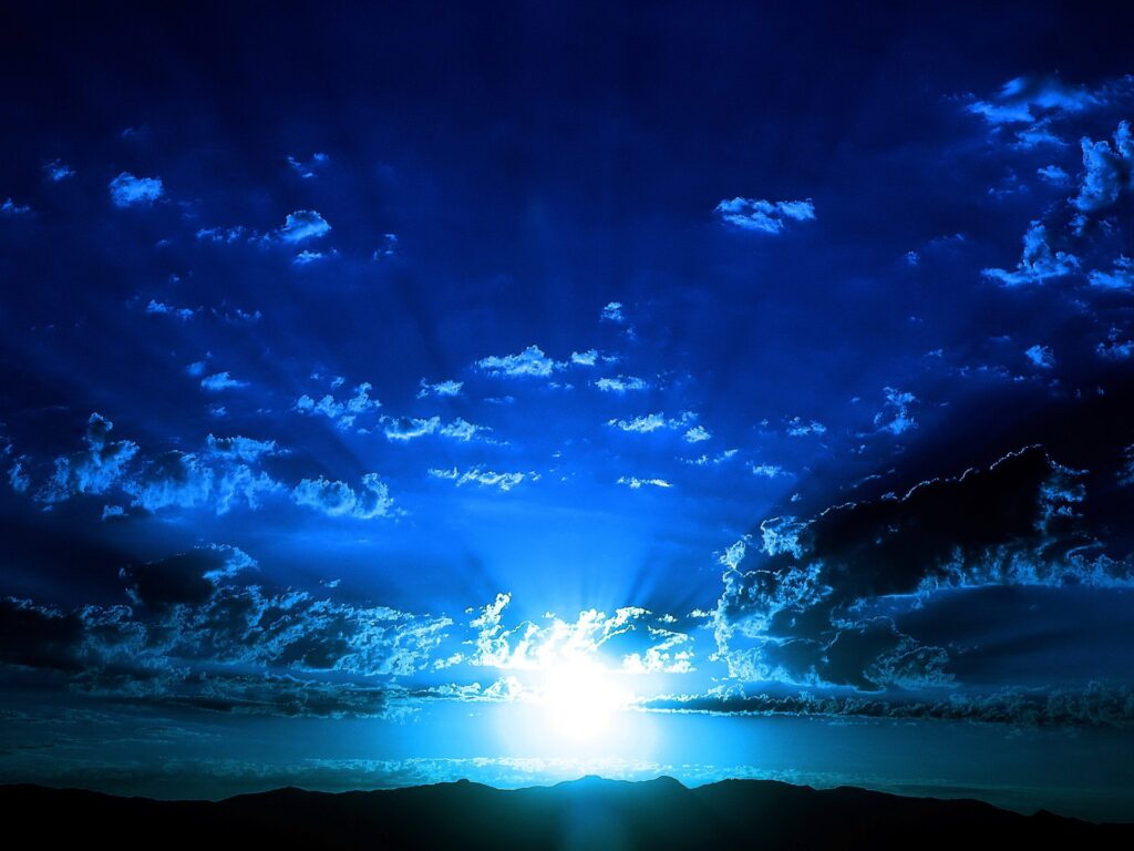 Morning sunlight over dark mountains with blue clouds serene nature wallpaper background