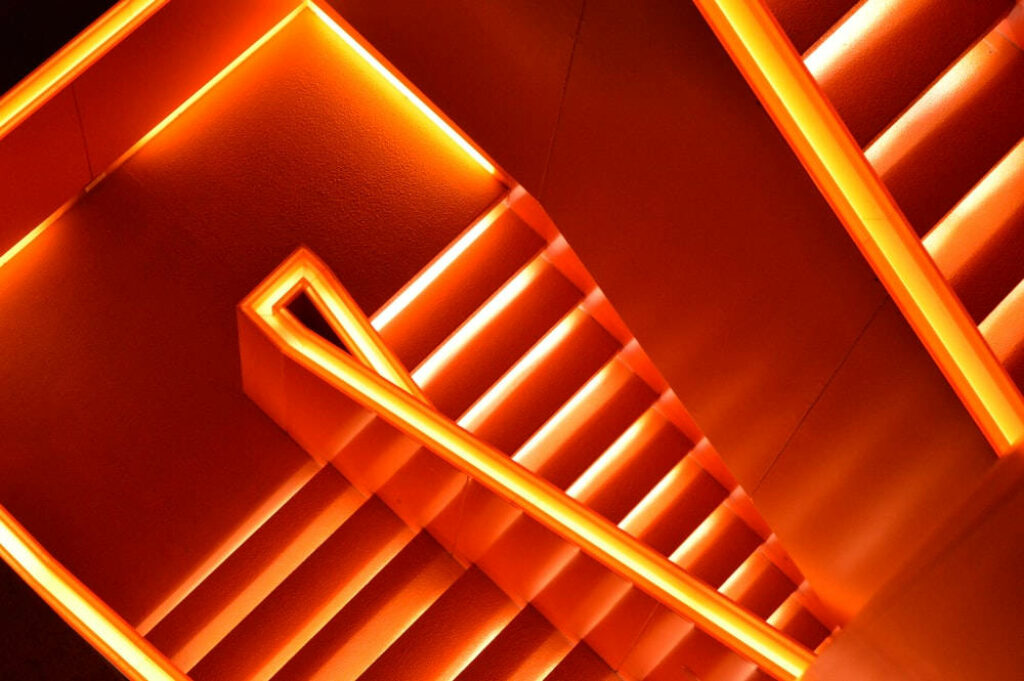 Glowing Pathways: Neon Orange Aesthetic Wallpaper Transforms Stairway with Luminous Lights